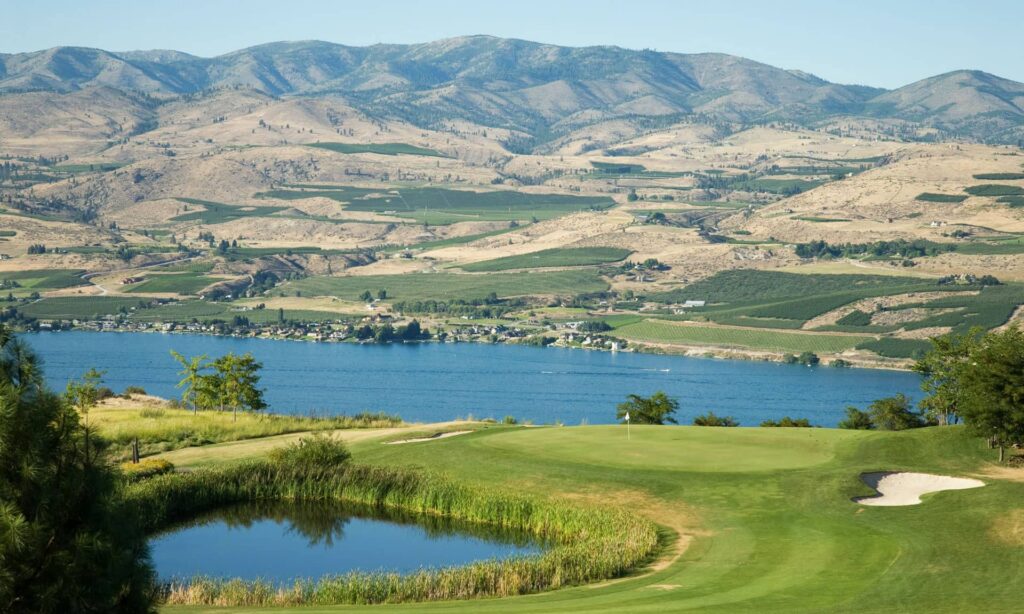 A golf hole with a white flagstick next to a pond