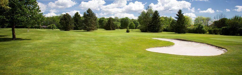 A view of a golf course with lots of trees in the background